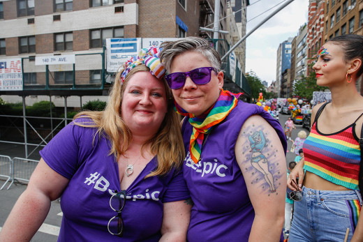 Two women posing closely together in purple #BeEpic shirts at the NYC Pride March.