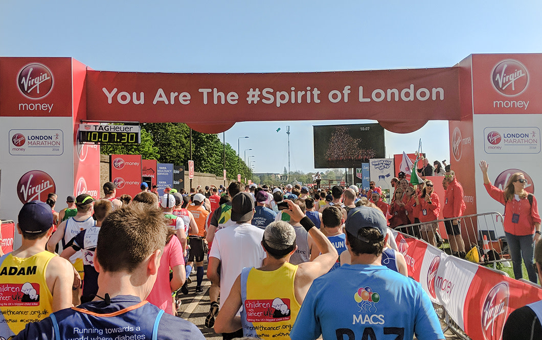 A crowd of runners going through the starting gate at the Virgin Money London Marathon
