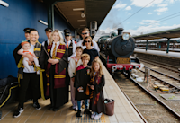Harry Potter fans stand together on a platform, getting ready to board the Audible Express vintage steam train in Sydney.