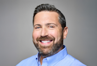 A headshot of Lee Jarit, who's smiling. Lee has a beard and is wearing a blue button-down shirt. 