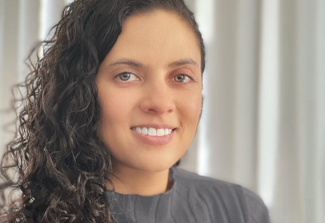 A headshot of Audible employee Nicole Weingartner, smiling to camera, wearing a grey sweater.