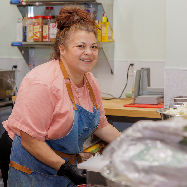 A woman stands in a kitchen prepping food.