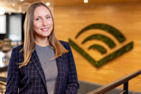 Audible employee Julia Phillips stands in the Newark office, the Audible chevron on the wall behind her.