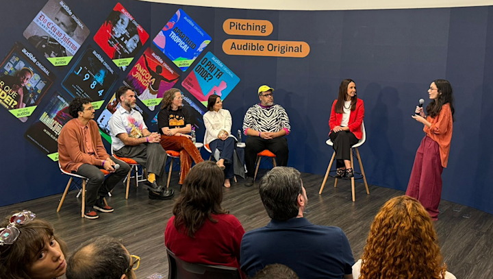 Mikaela Pasa pitches her team’s winning project to judges Leo Neumann, Chico Felitti, Paula Scarpin, Bianca Comparato and MM Izidoro, as Audible’s country manager for Brazil Adriana Alcântara looks on.