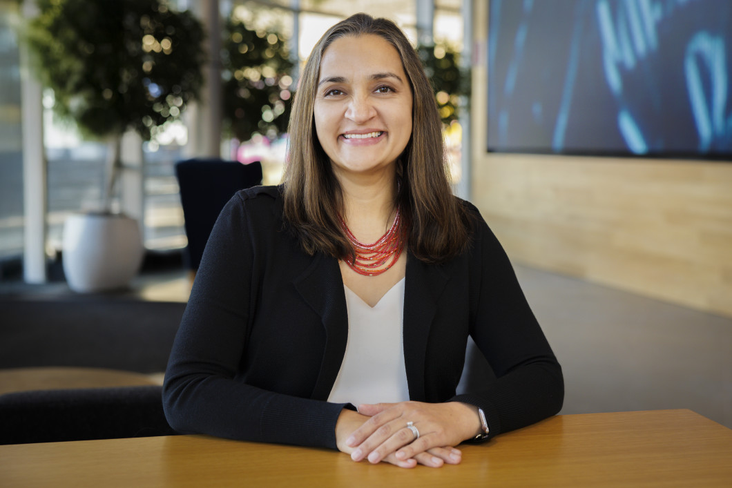 A photo of Sadaf Kazmi, who's seated at a desk and smiling. 