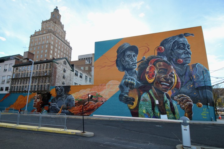 "Souvenir de la Voix," a mural created by Hans Lundy & Malcolm Rolling of YENDOR for Newark Artist Collaboration. Seen here is a young girl joyfully laughs while listening to the sounds of her ancestors.
