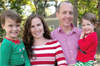 A young boy and girl are being held by their mother and father, posing for a photo. All are dressed in festive holiday clothing. This is the Wenks family.