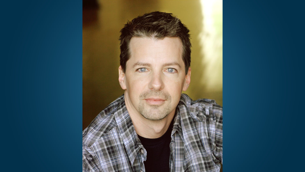 Actor Sean Hayes, seated, stares into the camera.
