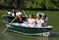 A photo of several people wearing Edwardian-era and fantasy clothing on rowboats in New York's Central Park. 
