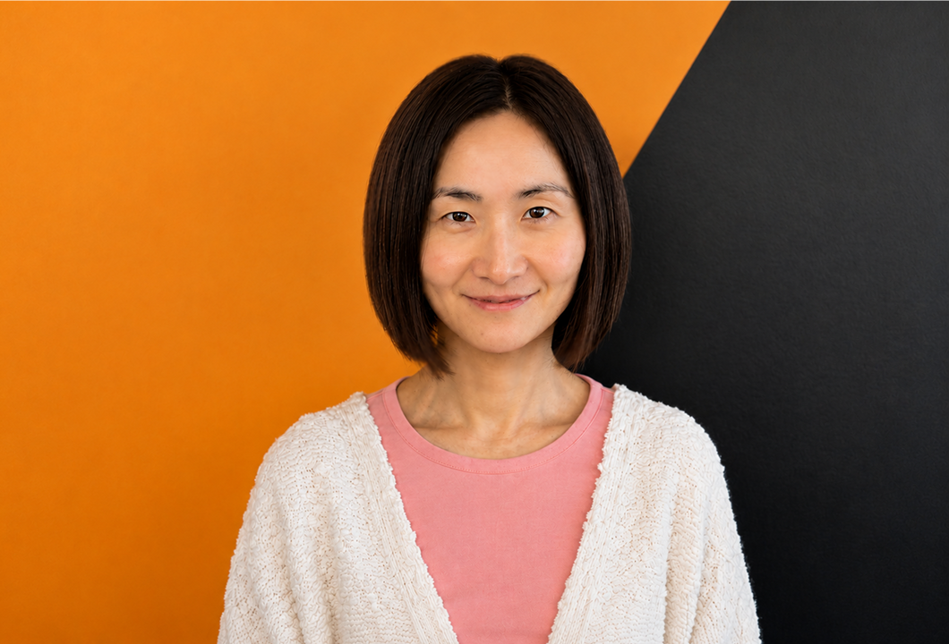 A headshot of Nina Liu. She had mid-length hair and is wearing a white cardigan over a pink shirt.