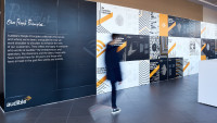 An employee dressed in all black is walking past a wall in our lobby that outlines all of our people principles and our new design featuring lines in various patterns for each of our principles.