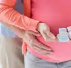 Pregnant woman holding shoes for twins