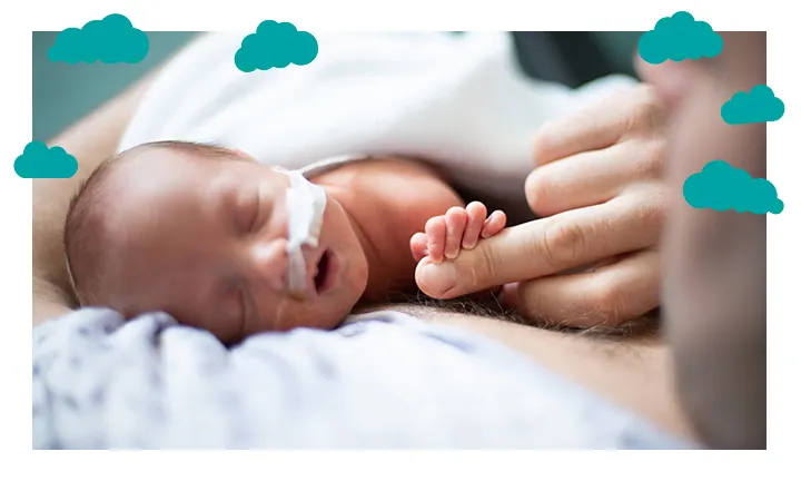 PREEMIE BABY ASLEEP ON ITS SIDE WITH NASAL TUBE ATTACHED AND HOLDING ONTO ADULT FINGER