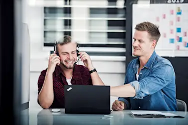 Hier sehen Sie zwei Homeda Mitarbeitende vor einem Laptop.