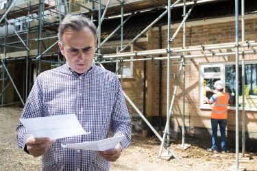 Neu bauen oder kaufen - Hier sehen Sie einen Eigentümer, der vor der Entscheidung steht Haus bauen oder kaufen.