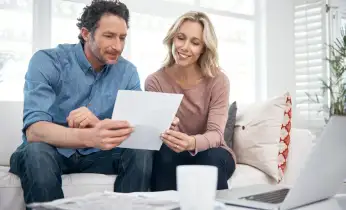 Hier sehen sie einen Mann und eine Frau, die ein Dokument über Anschlussfinanzierung lesen. 