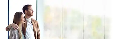 Immobilienbesitzer Pärchen schaut aus dem Fenster.