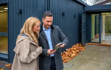 Homeday Maklerin analysiert Marktdaten und den Immobilienwert im Beratungsgespräch mit Eigentümern auf einem Tablet.