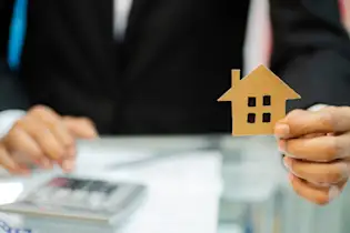 Hier sehen Sie das Bild eines Eigentümers, der die Maklerkosten bei einem Hausverkauf berechnet.