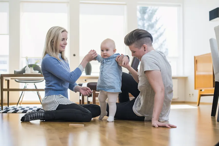 Baukindergeld 2023: Hier sehen Sie Eltern, die auf dem Boden ihrer Wohnung sitzen und mit ihrem Baby spielen. 