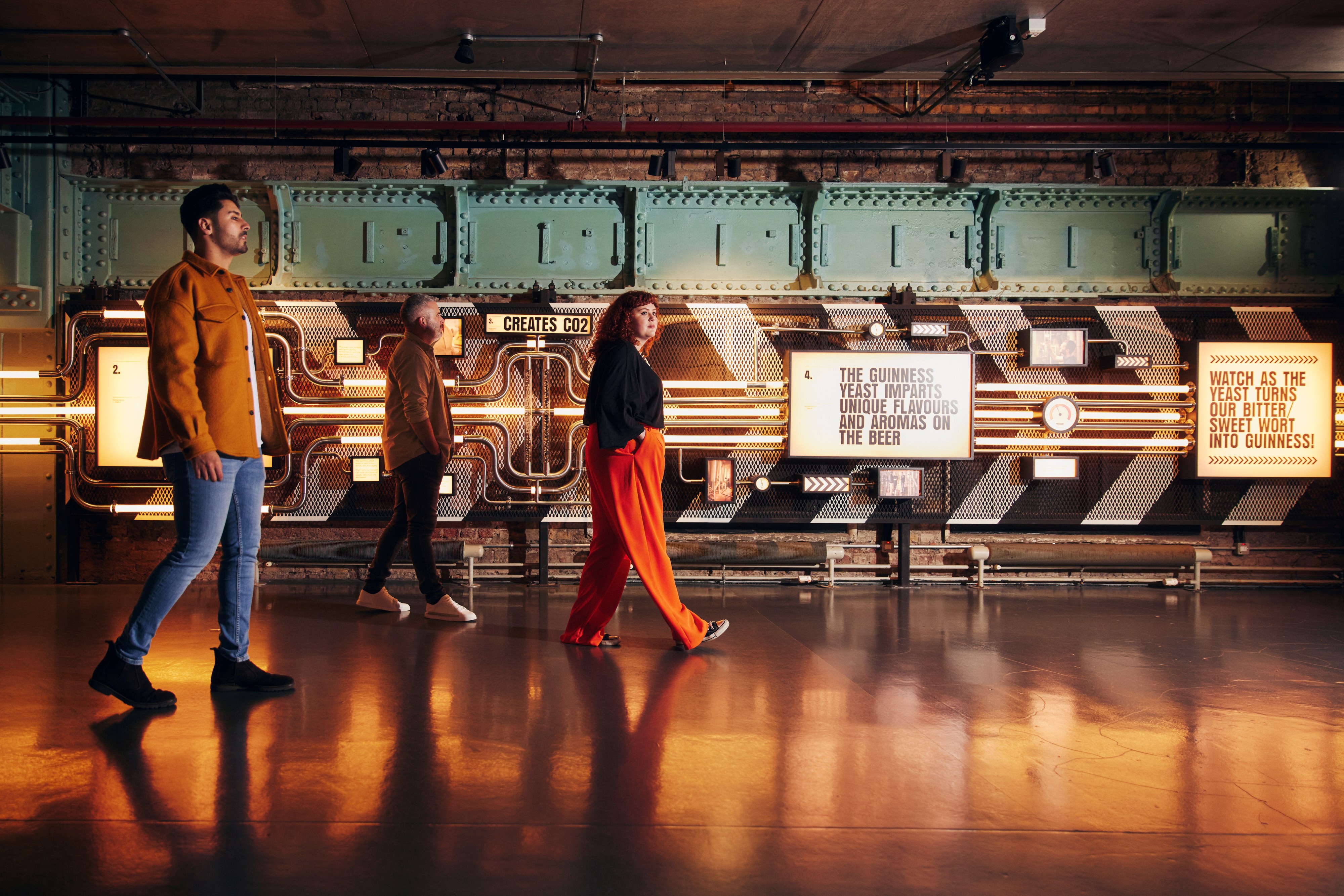 3 people going along the room in Open Gate London. Sign with the text "Creates CO2"