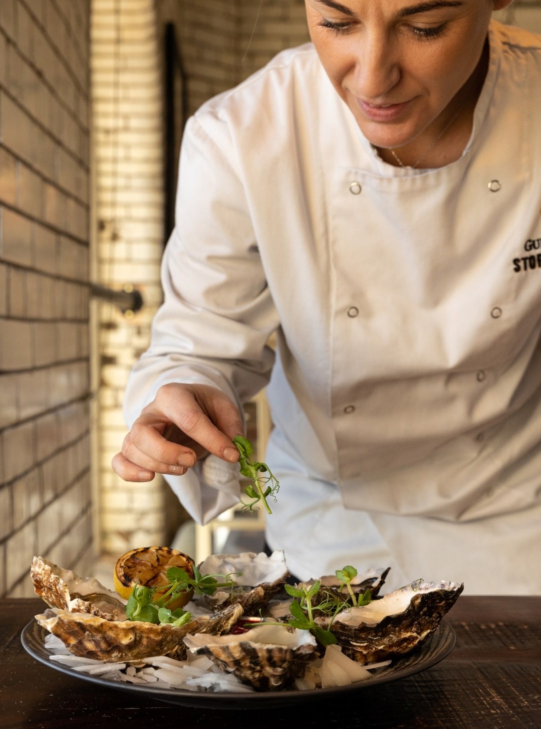A chef puts the finishing garnishes onto a plate of oysters.
