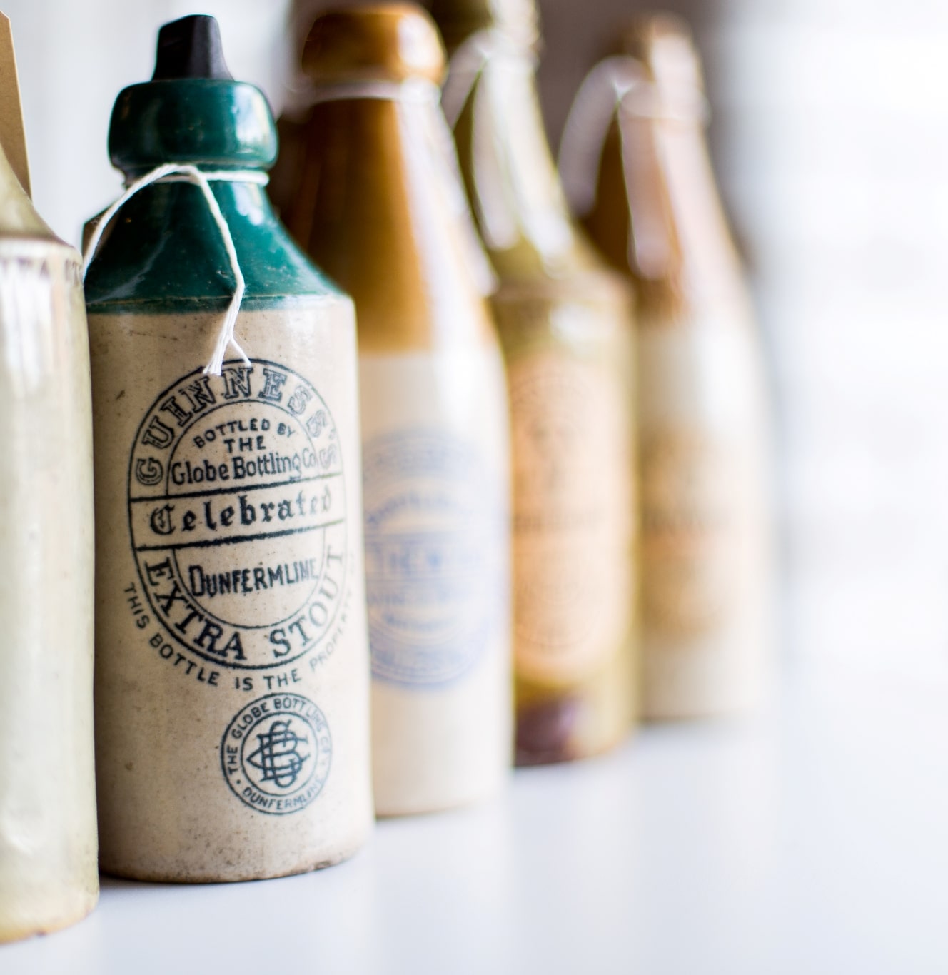 Vintage ceramic Guinness branded bottles are lined up against a wall.