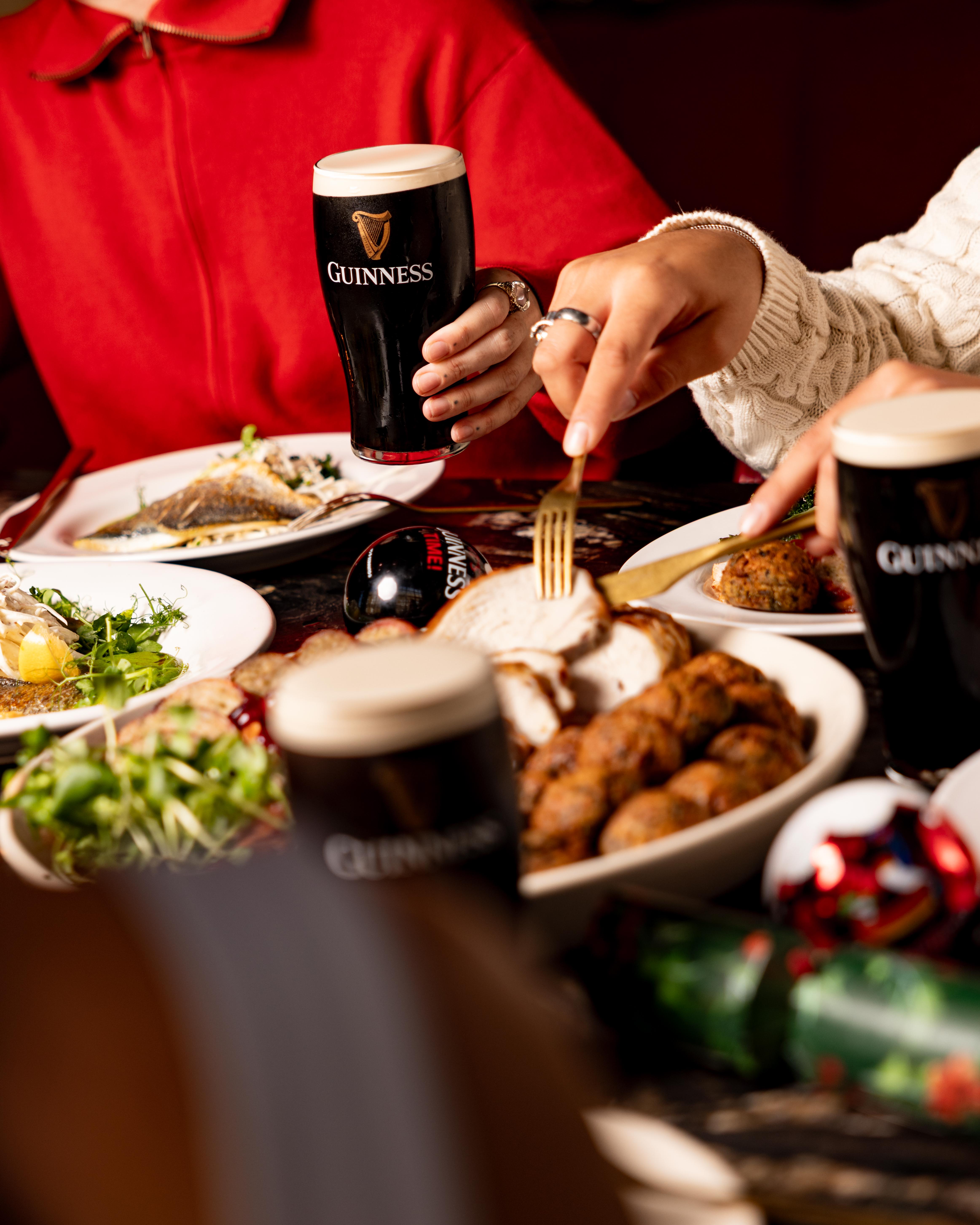 A close up of a group of people eating in a restaurant, eating christmas dinner and drinking Guinness