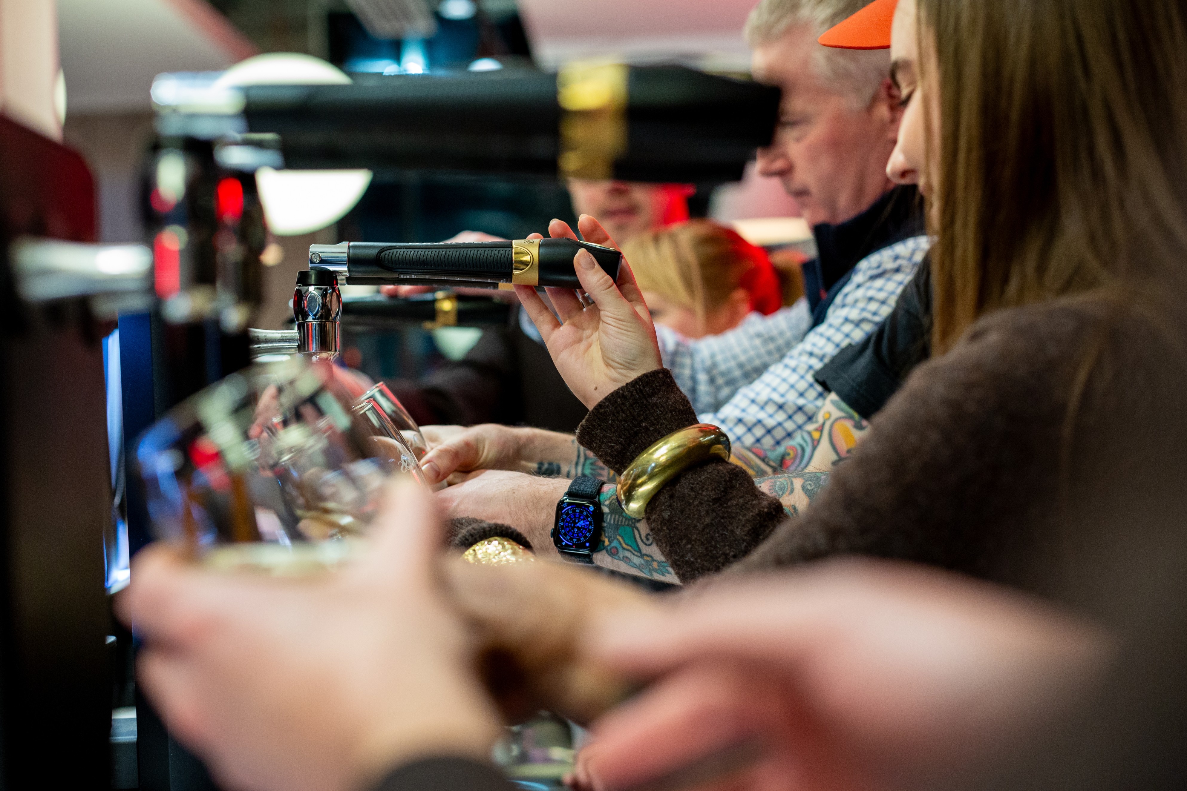 People lined up behind a bar pouring pints of Guinness
