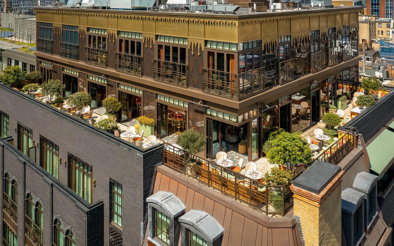 An ariel view of the beautifully designed rooftop restaurant, Flute, in Broadwick Soho, complete with cushioned seating and potted trees
