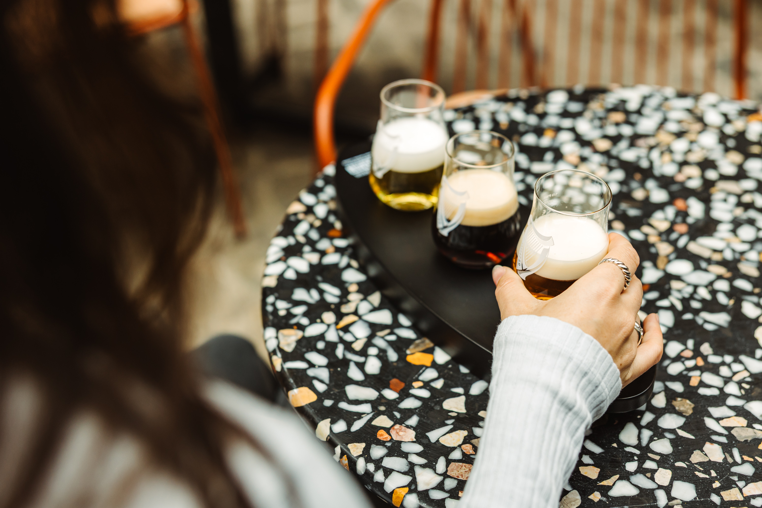 Over the should view of 3 small beers on a wooden padel on an outside table