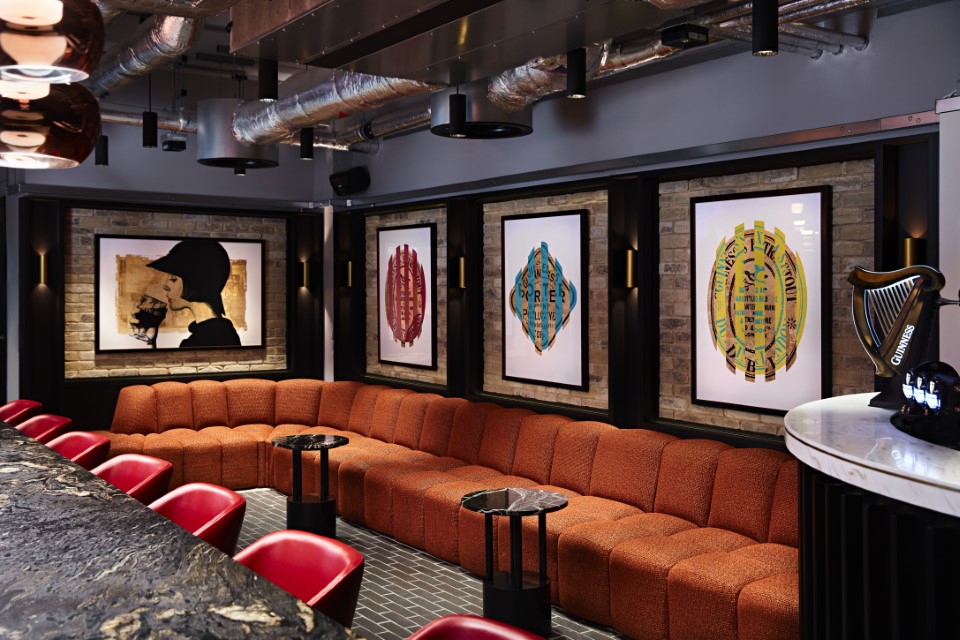 Private dining room, with a table, sofas and a bar with a Guinness tap and artwork on the walls