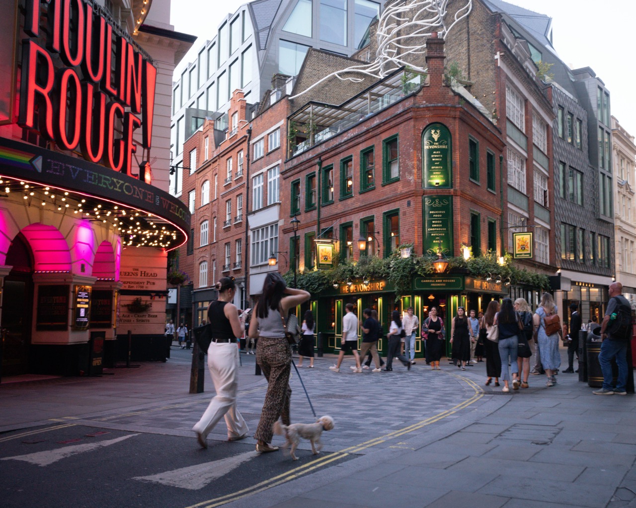 A street view of the Devonshire pub and restaurant looking busy with people drinking Guinness outside and the rooftop restaurant visible.