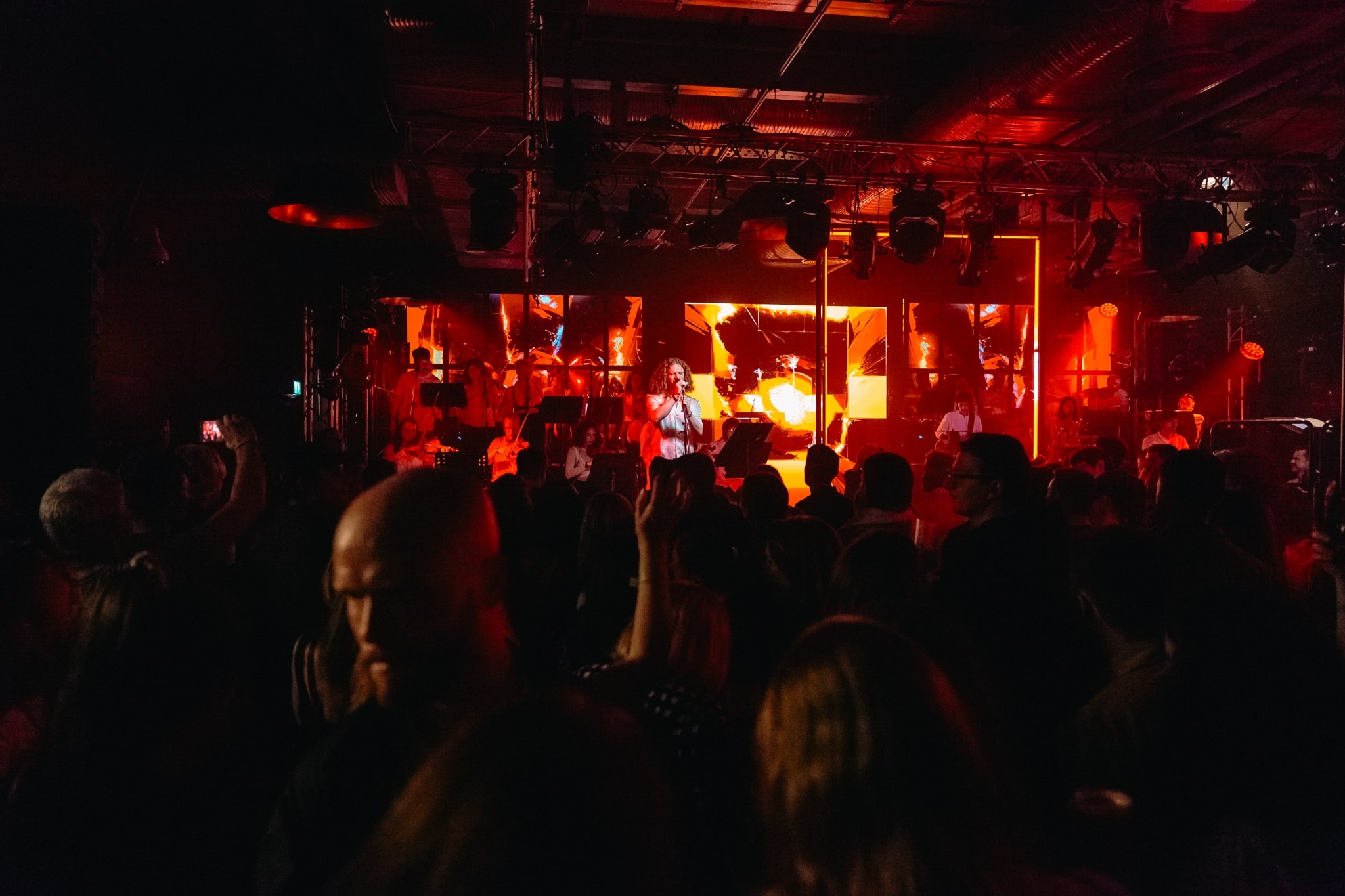 A man performs for an audience with a small orchestra behind him.