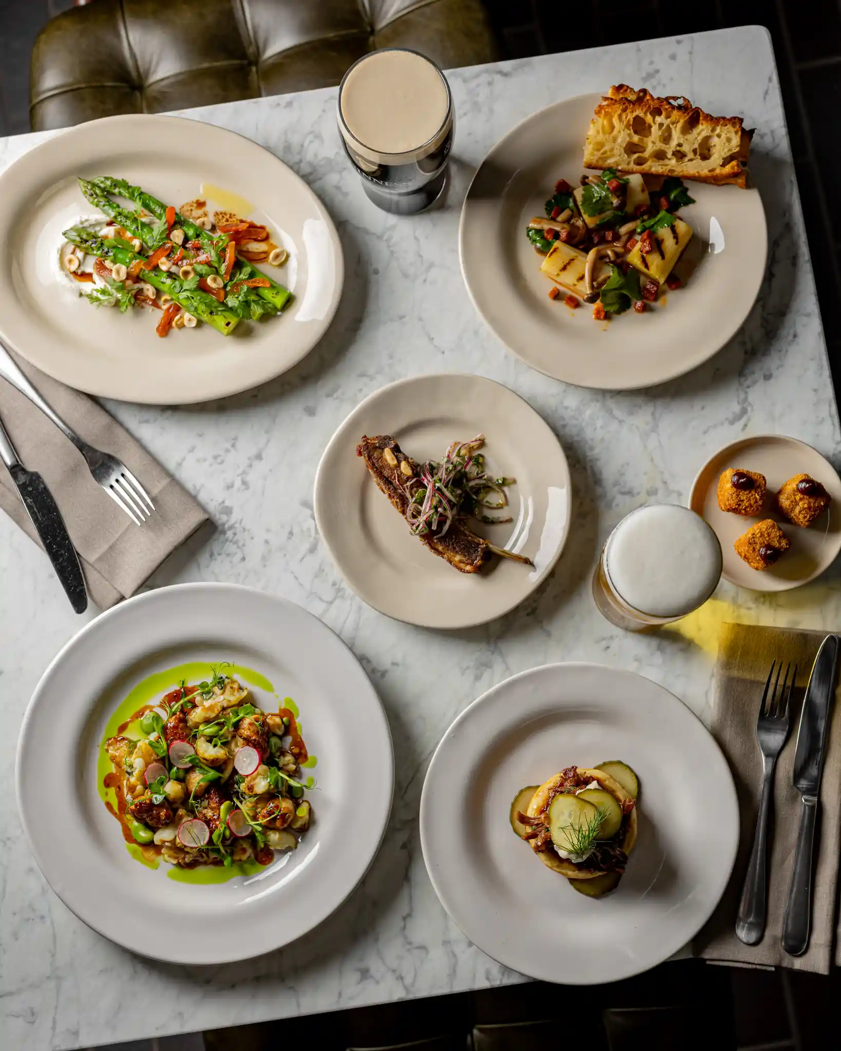 A white marble table with plates of food and beers