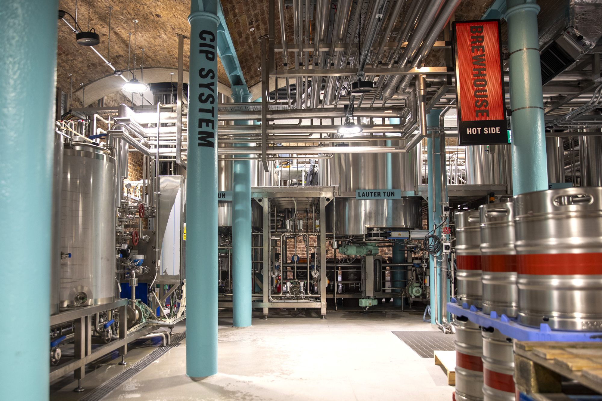 A view inside the working micro-brewery at Guinness Open Gate Brewery London, filled with metal kegs and technical equipment
