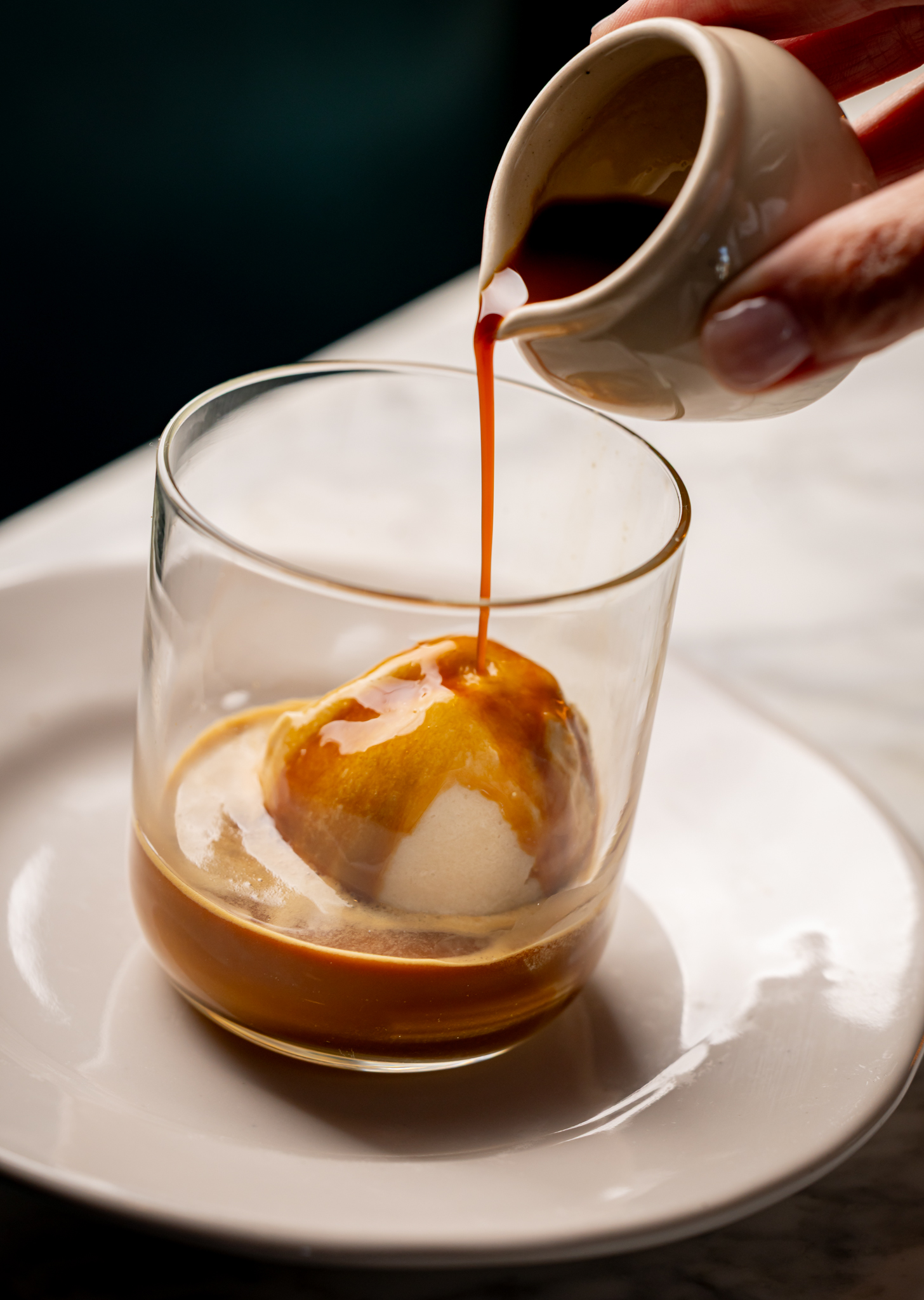 A velvety coffee is pours over ice cream in a crisp glass in The Porter's Table restaurant in Central London