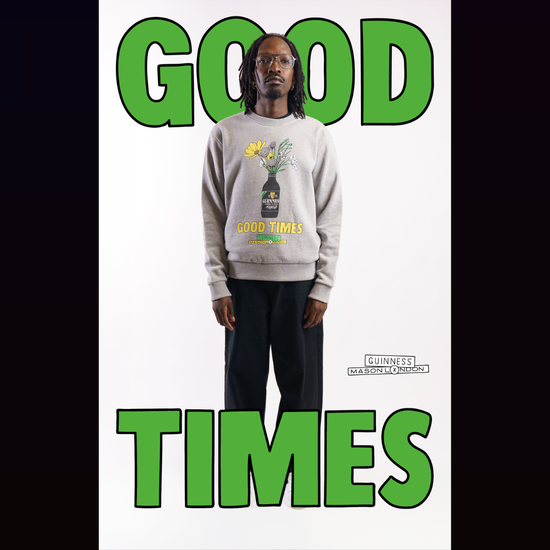 A man wears a grey sweatshirt with a Mason London x Guinness illustration of a Guinness bottle vase with flowers and the words Good Times