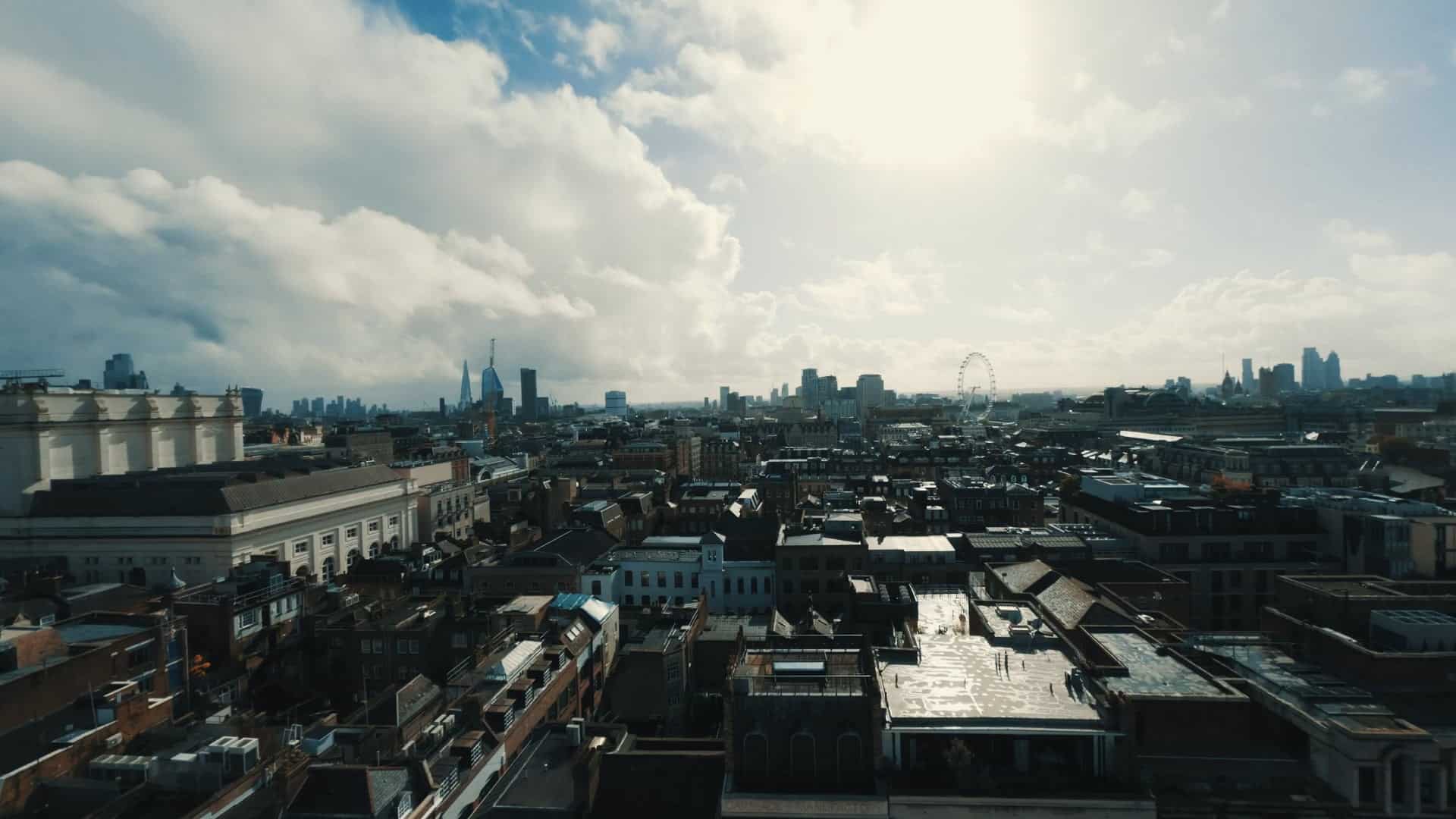 A high-angle view of the London skyline under a cloudy sky, featuring a mix of historical and modern buildings.