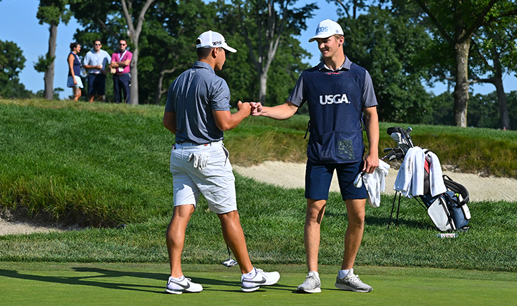 Karl Vilips gets a fist bump from his caddie after putting on hole three during the first round of stroke play at the 2022 U.S. Amateur at The Ridgewood Country Club in New Jersey. Photo: Grant Halverson/USGA.