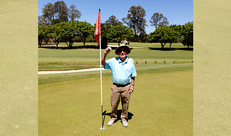 99-year-old golfer Hugh Brown proudly holding the ball aloft after his hole-in-one on the 5th hole of Indooroopilly Golf Club's Blue Course.