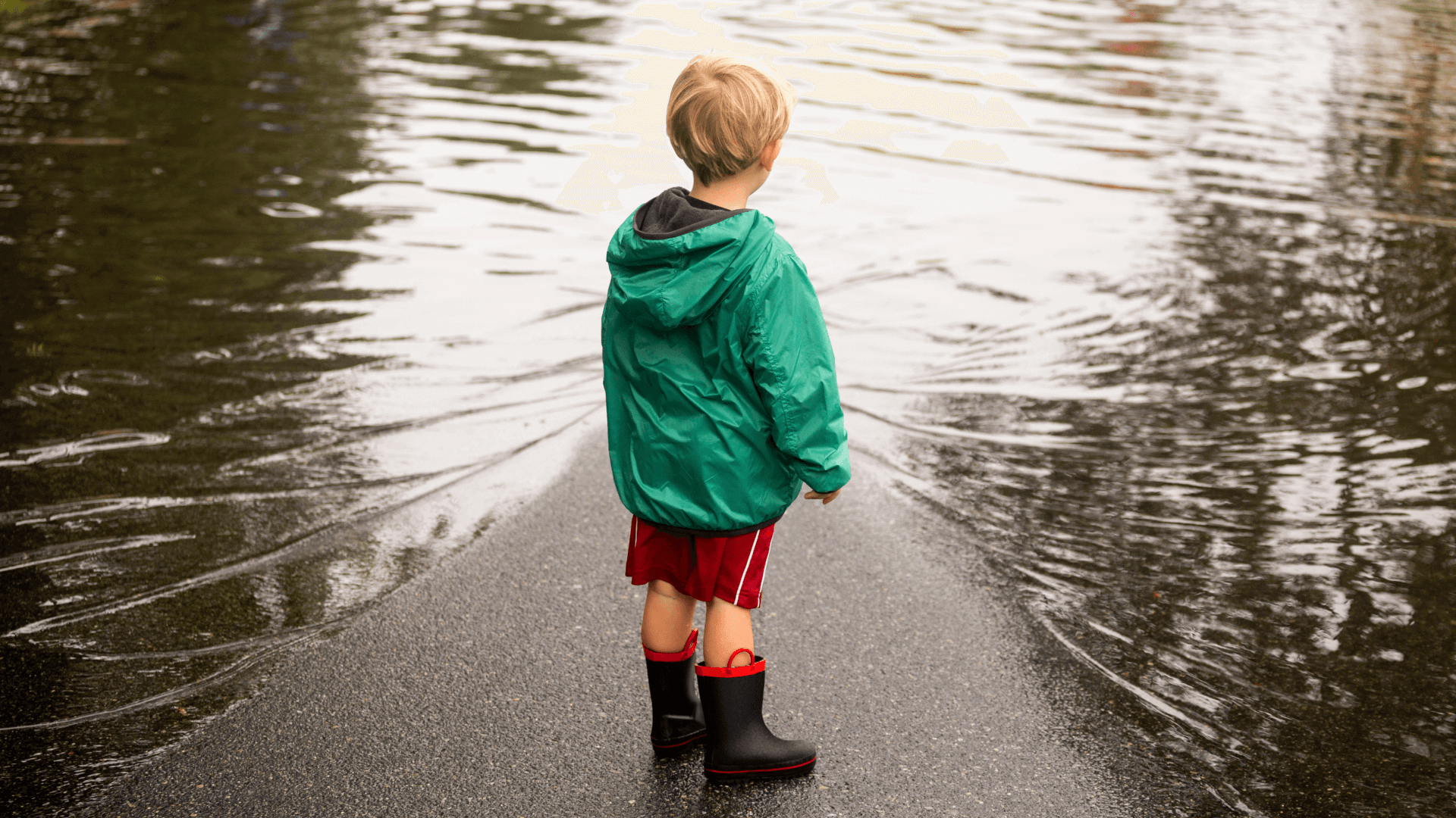 boy wearing puddles near flood