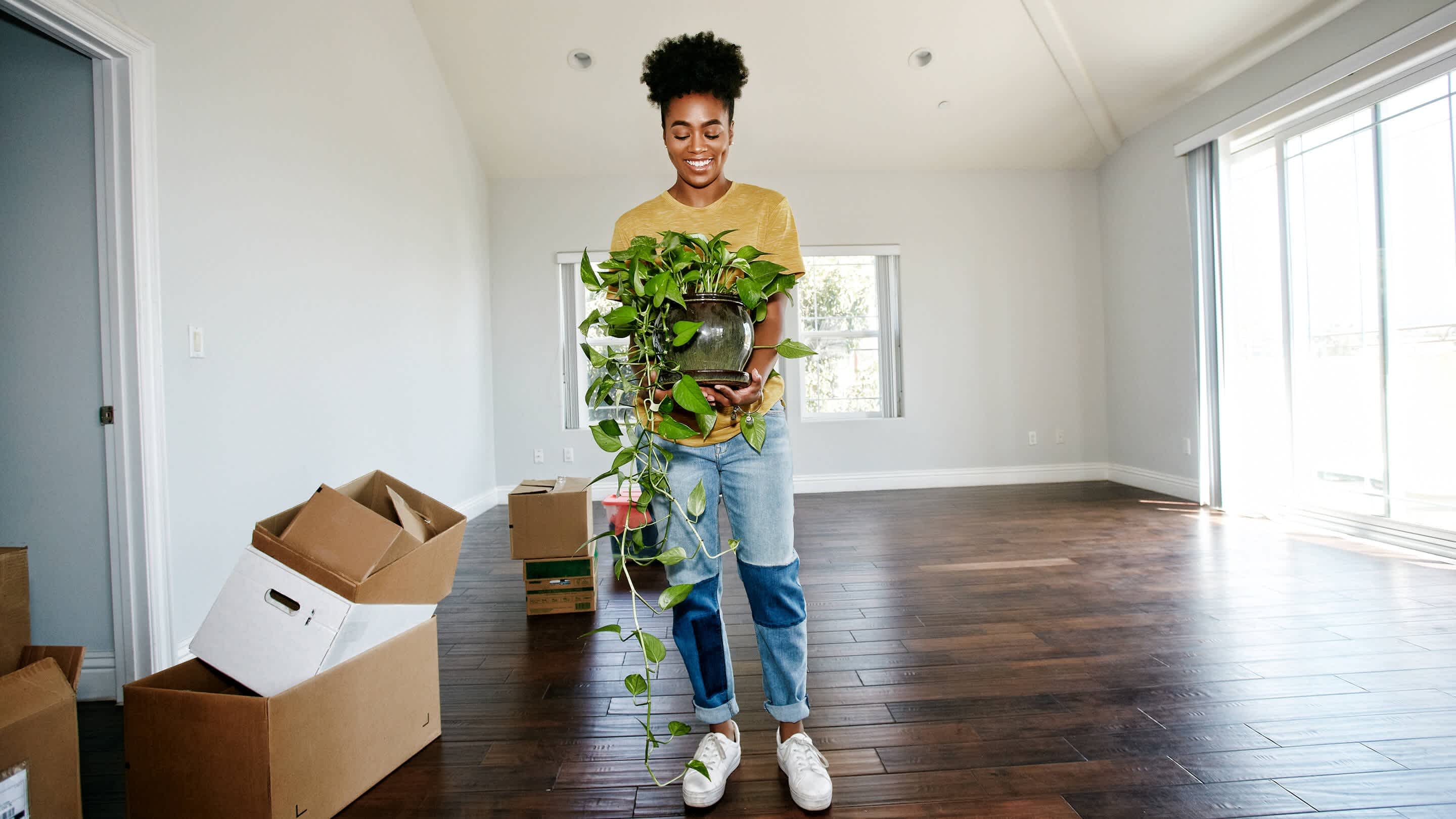 a woman holds a plant in an empty house