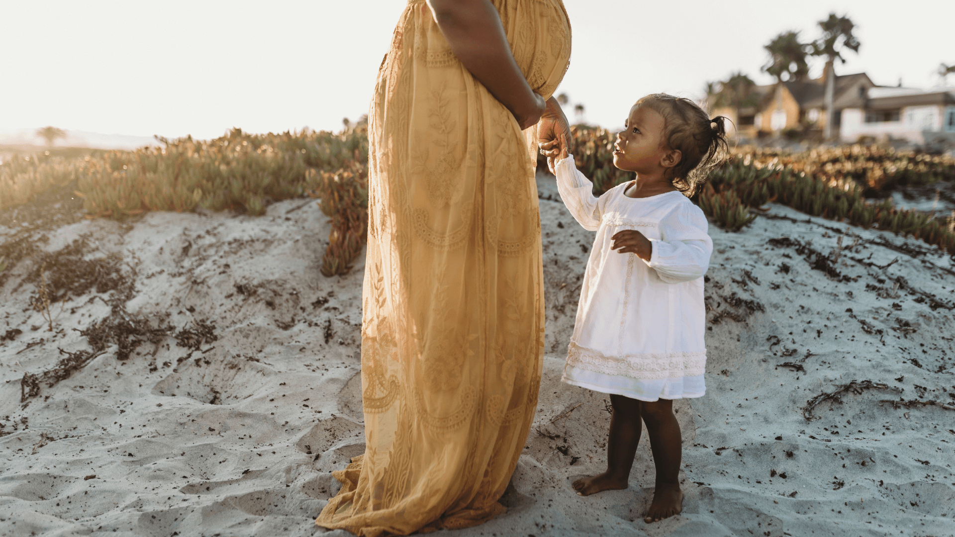 Side view of young toddler girl with mother's pregnant belly