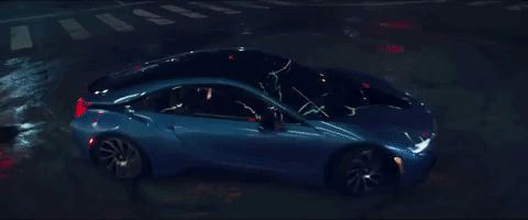 Kendrick and Rihanna are singing and laughing, doing donuts at an intersection in their BMW i8.
