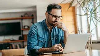 Man looking at laptop, thinking.