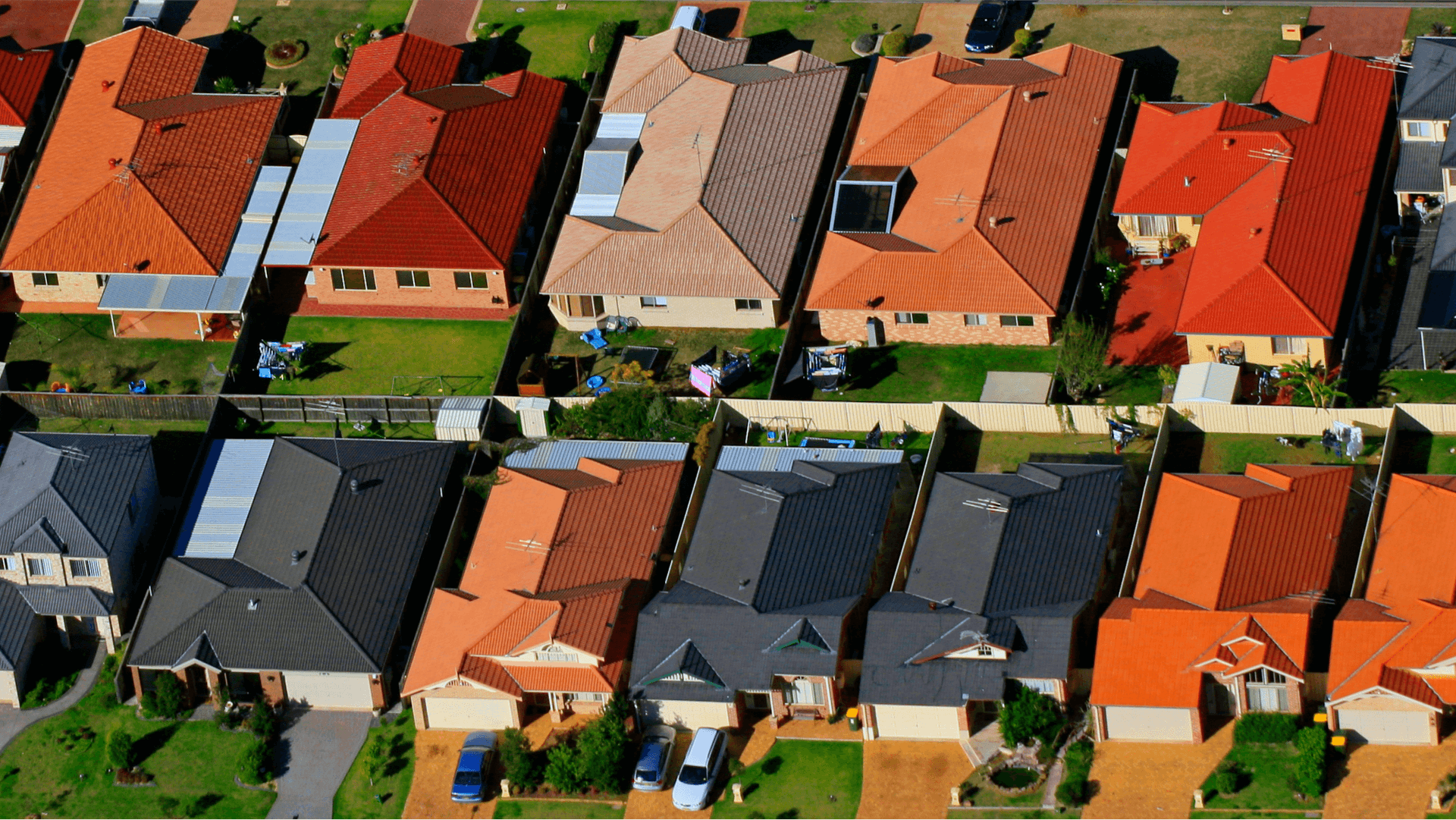 aerial view of suburban block with orange-roofed houses with green lawns