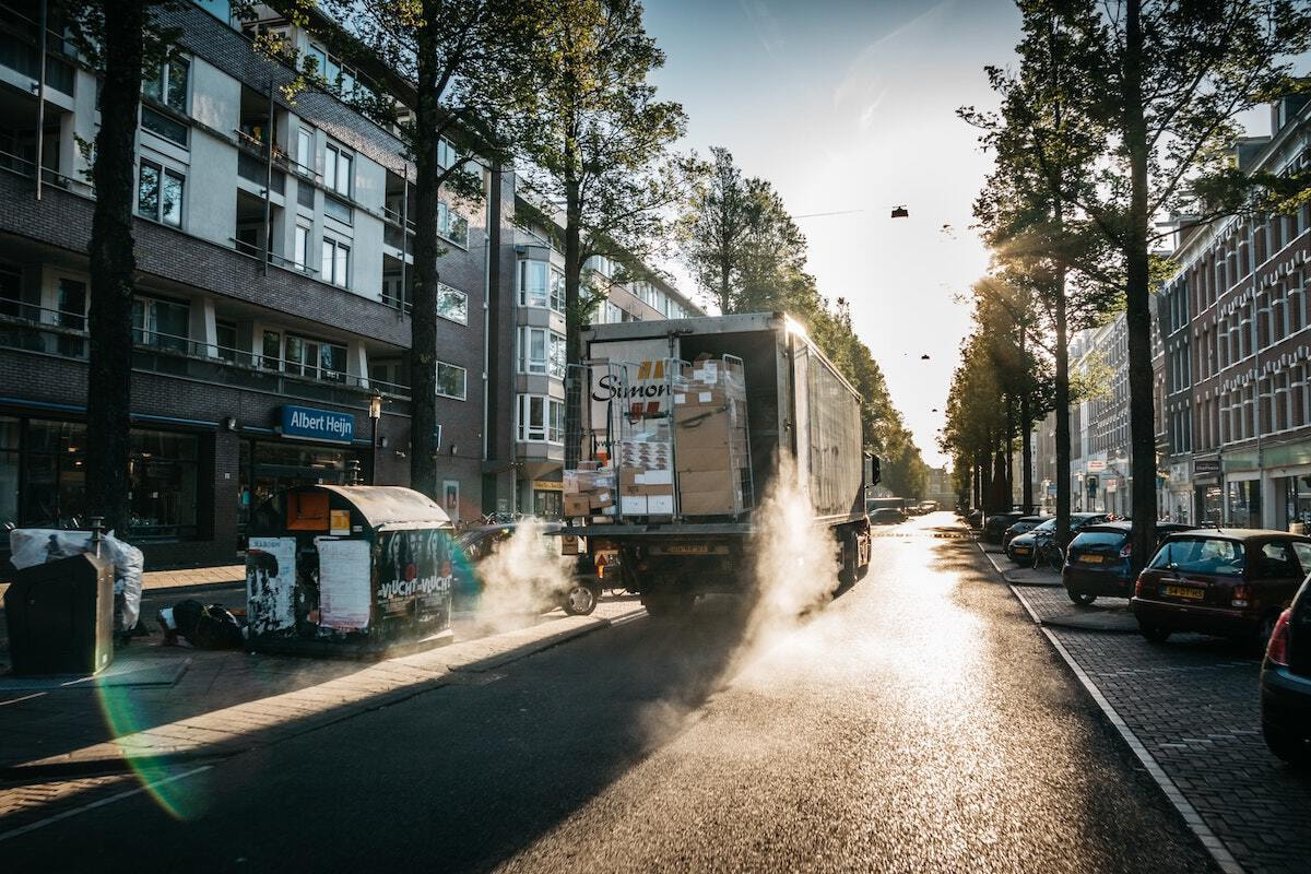 Ein Lieferwagen fährt mit offener Frachttür eine Straße in einer europäischen Stadt entlang.