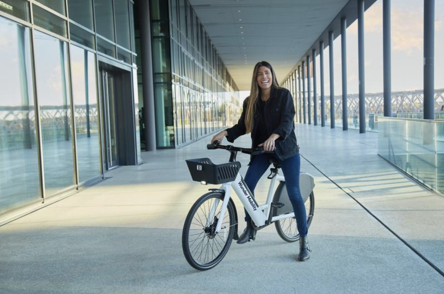 Caucasian female person smiling and riding an e-bike.