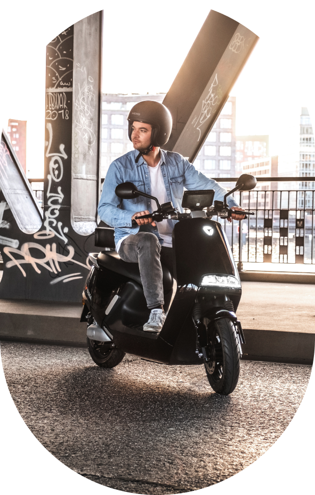 A caucasian man riding electric moped.